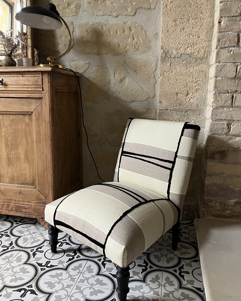 Chauffeuse tapissée d'un tissu rayé, sol en carreaux de ciment